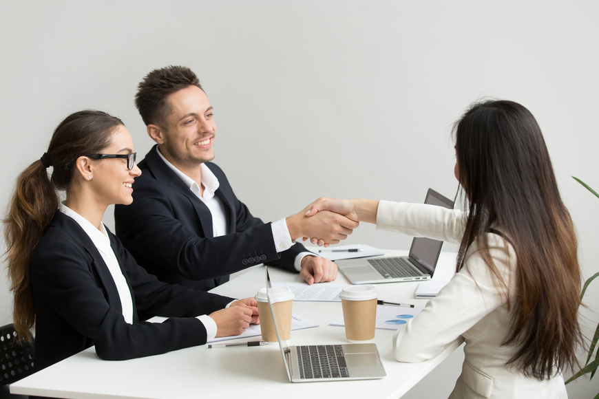 Friendly partners handshaking at group meeting thanking for succ